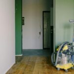Heavy-duty vacuum cleaner stands in a freshly painted hallway, ready for post-renovation cleanup.