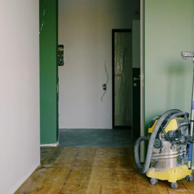 Heavy-duty vacuum cleaner stands in a freshly painted hallway, ready for post-renovation cleanup.