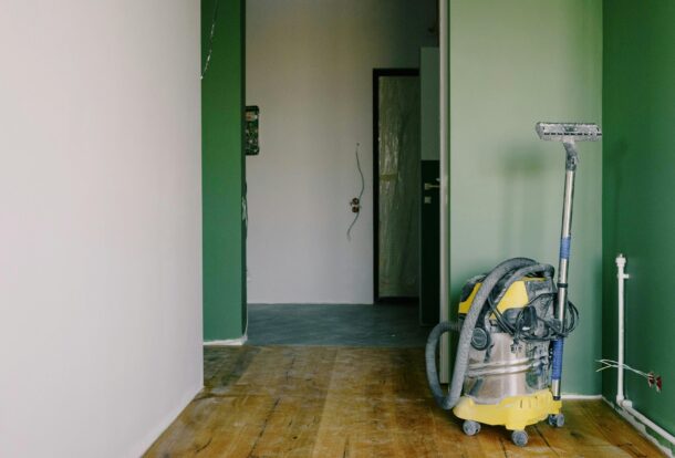 Heavy-duty vacuum cleaner stands in a freshly painted hallway, ready for post-renovation cleanup.
