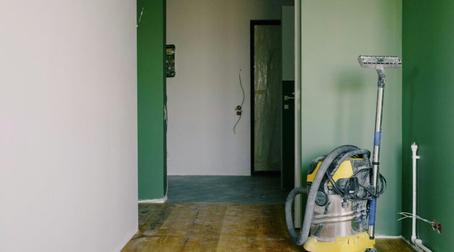 Heavy-duty vacuum cleaner stands in a freshly painted hallway, ready for post-renovation cleanup.