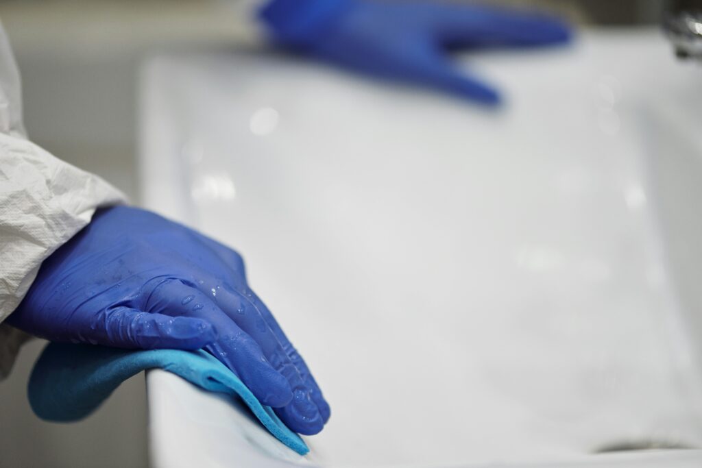 Cleaning specialist wiping a sink with a blue cloth during post-renovation deep cleaning.