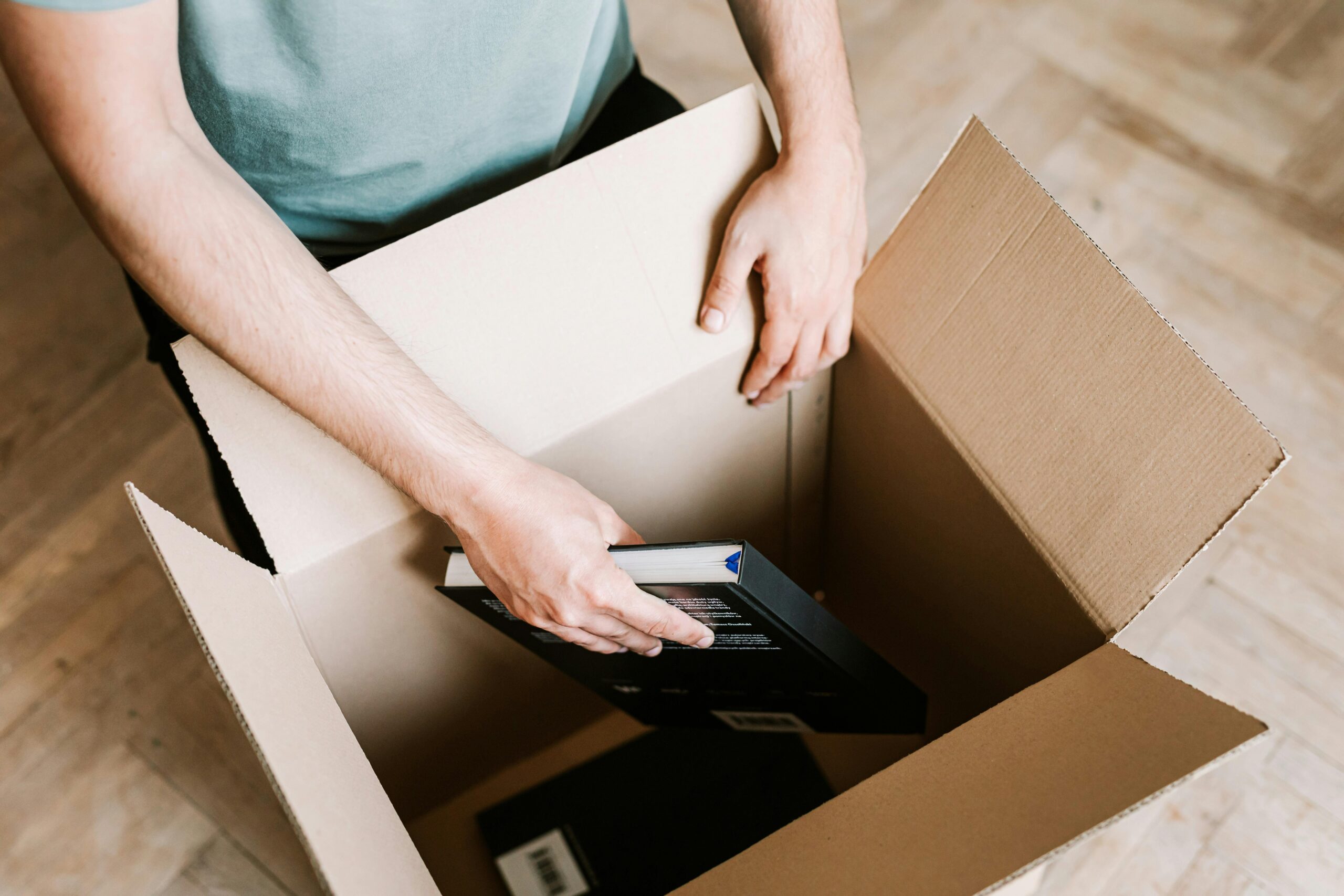 Man packing a cardboard box with books while preparing to move out